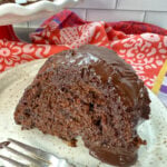 A piece of chocolate cake with plenty of chocolate flavor on a beige plate. The cake has chocolate frosting on top.