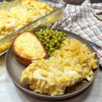 Easy 4-Ingredient Chicken And Rice Casserole Dinner on a plate with peas and a piece of bread.