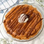 Chocolate chip cookie pie with a scoop of vanilla ice cream on top and chocolate syrup drizzled over it.