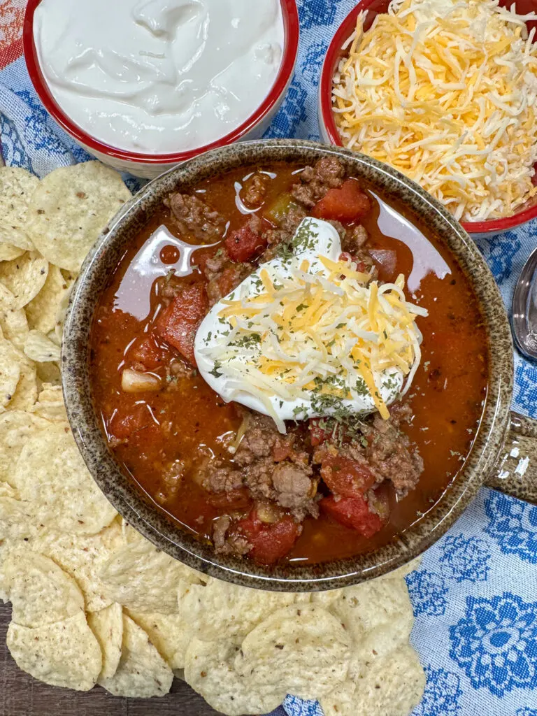 Beanless chili on the counter with sour cream and shredded cheese on top.