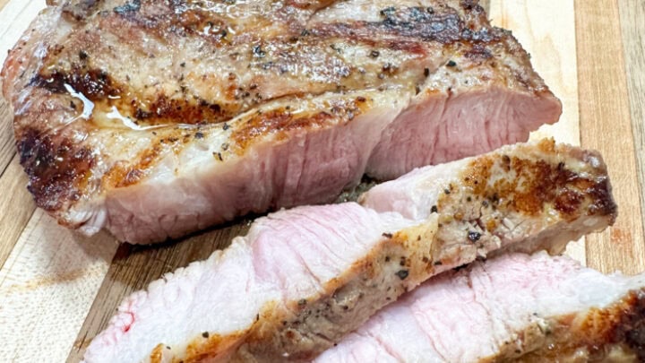 Sliced pork shoulder steak on a cutting board.