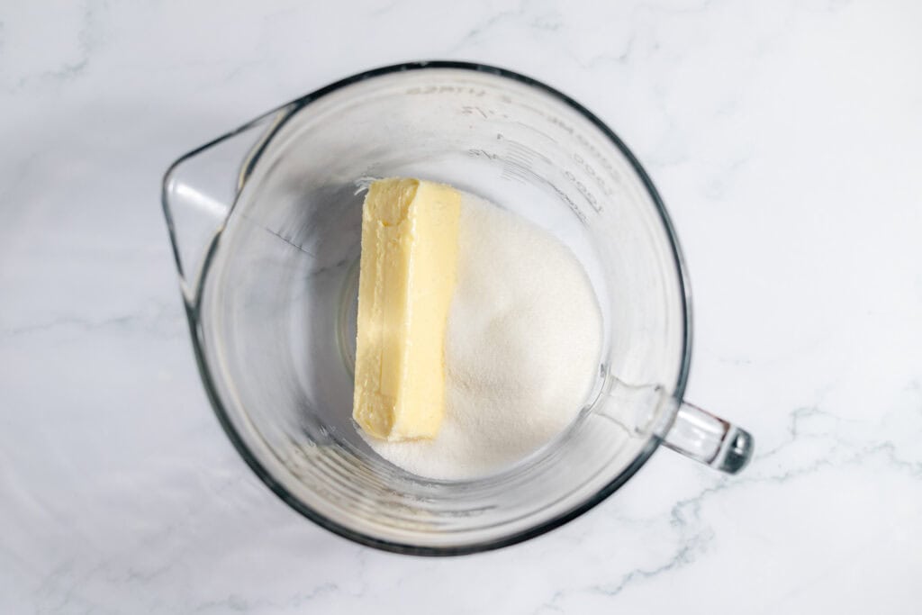 Butter and sugar in a clear glass mixing bowl. 