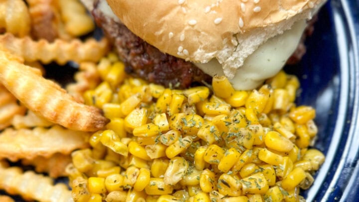 seasoned corn on a blue plate with a hamburger and french fries