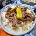Mississippi pot roast on a plate. The pot roast is on top of mashed potatoes.
