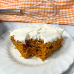 Pumpkin dump cake on a white plate. There's a bite taken out of the piece.