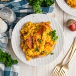 Corn casserole on a white plate with two forks next to the plate. There's a salt and pepper shaker next to the plate.