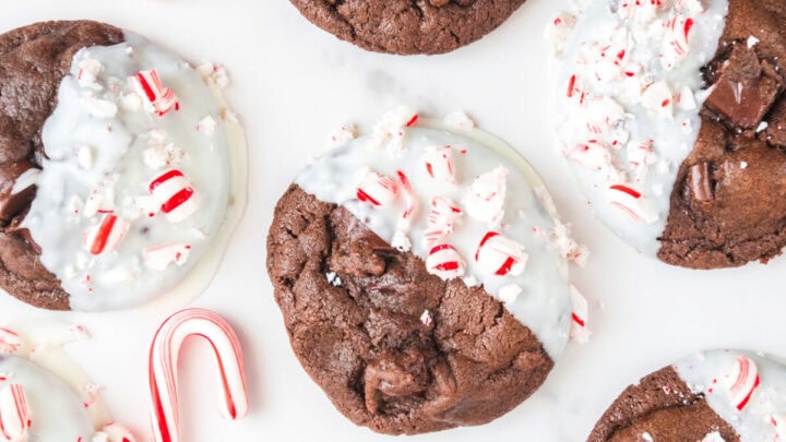 Double chocolate peppermint cookies on a white counter. There are two small candy canes sitting next to the cookies.