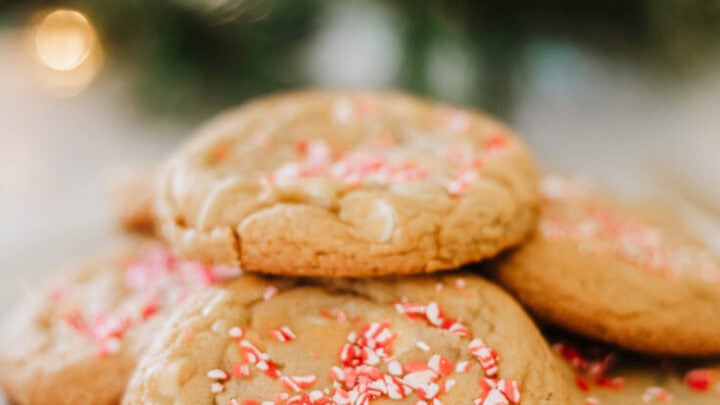peppermint cookies stacked on three white plates. There is a christmas tree in the background.