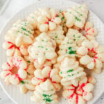 Shortbread cookies on a plate with red and green sprinkles. There are some sprinkles in a bowl next to the plate.
