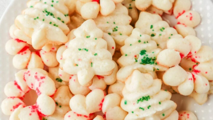 Shortbread cookies on a plate with red and green sprinkles. There are some sprinkles in a bowl next to the plate.