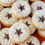 Linzer cookies stacked on top of a red plate.