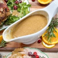Turkey gravy in a white gravy boat next to turkey.