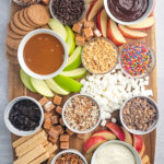 A full charcuterie board with apples, dips, marshmallows, and more.