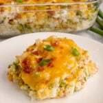 Loaded cauliflower casserole recipe on a white plate.