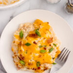 Mashed potato casserole on a white plate with a fork.