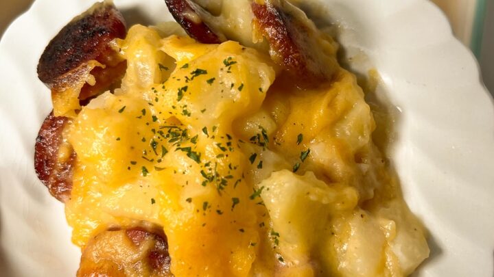 Potato sausage and casserole with cheese on a white plate.