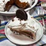 Mud pie slice on a white plate with an Oreo sitting on top.
