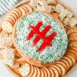 Spinach dip surrounded by crackers on a plate.