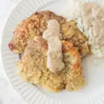 country fried steak on a white plate with rice and gravy.