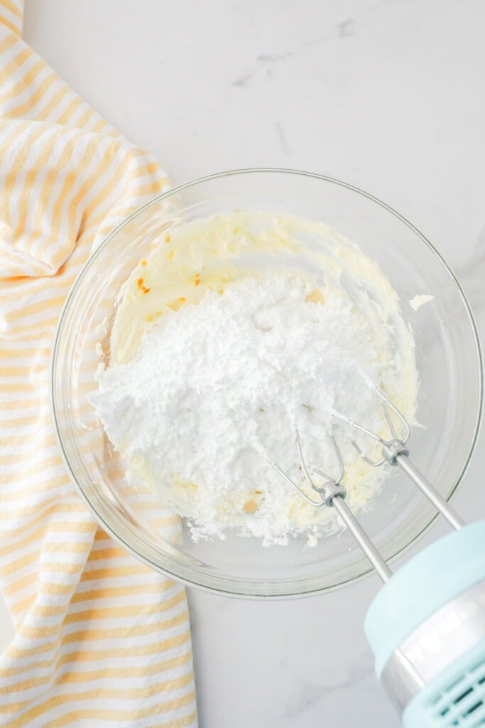 Adding ingredients to a bowl to make frosting.