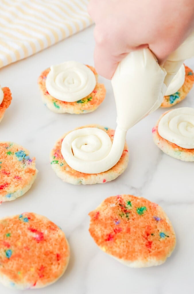 Piping frosting onto cookies.