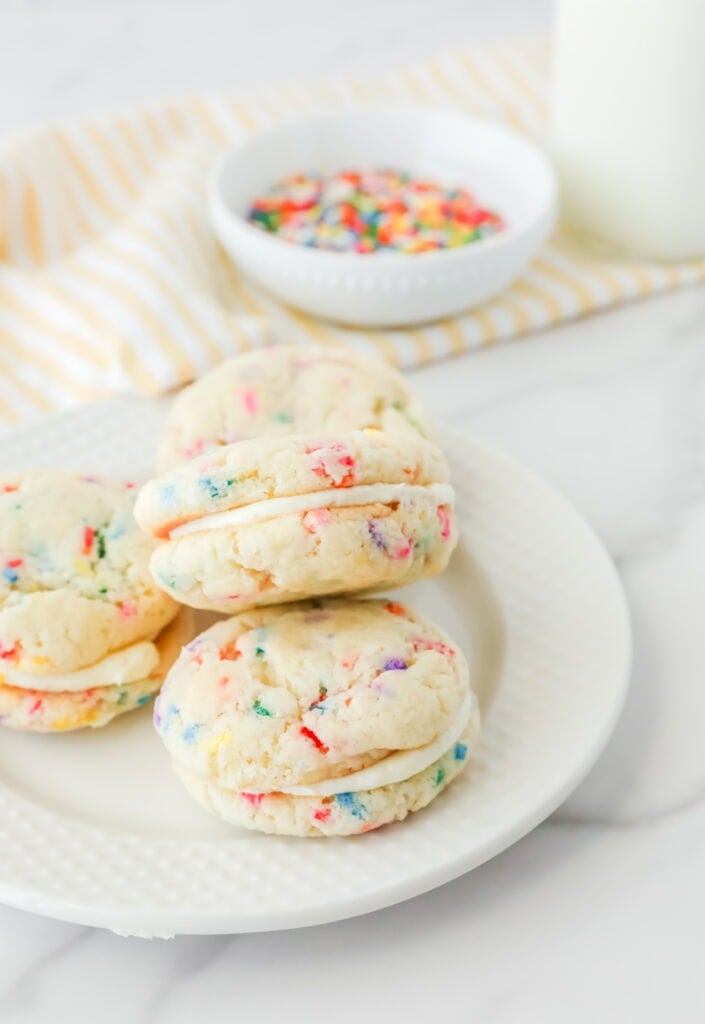 Whoopie pies with frosting in the middle on a white plate.