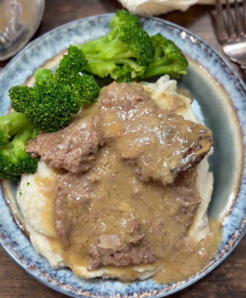 Cube steak on a plate with broccoli.