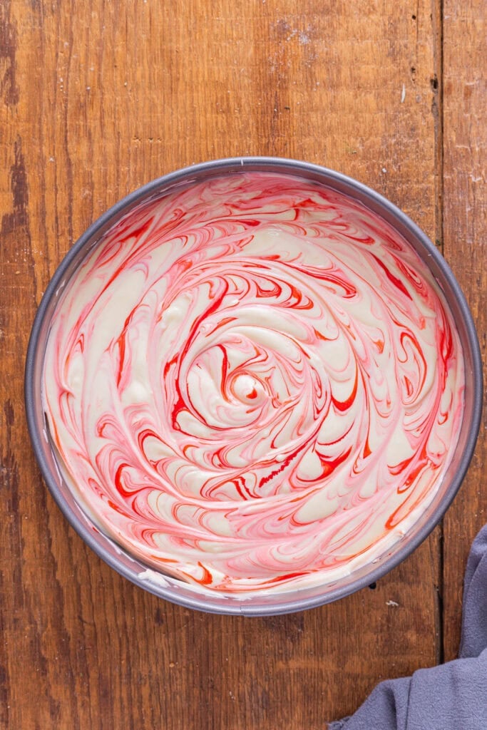 Red velvet cheesecake batter in a springform pan on a counter