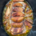 Cooked pork roast with apples in a slow cooker.
