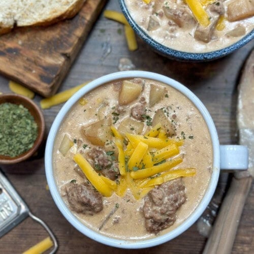 Cheeseburger soup in a bowl with shredded cheese on top.