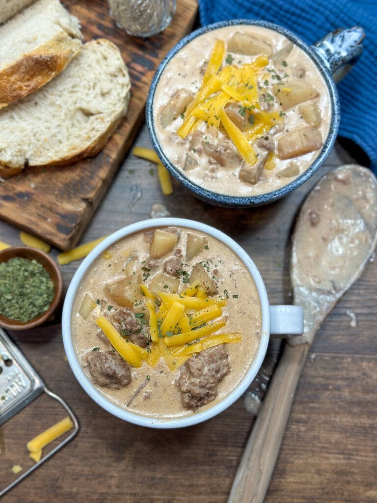 Crockpot cheeseburger soup on the counter. There are two bowls of soup next to some bread.