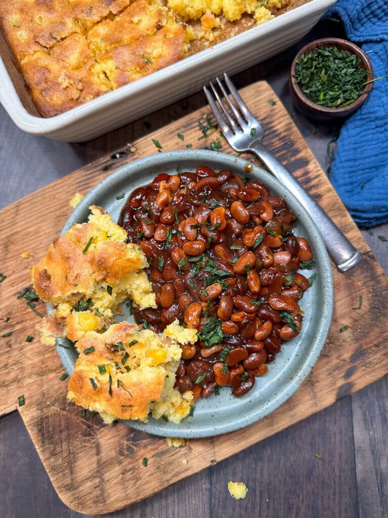 Slow cooker bbq baked beans on a plate with cornbread. 