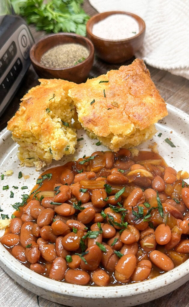 Slow cooker bbq beans on a plate with cornbread.