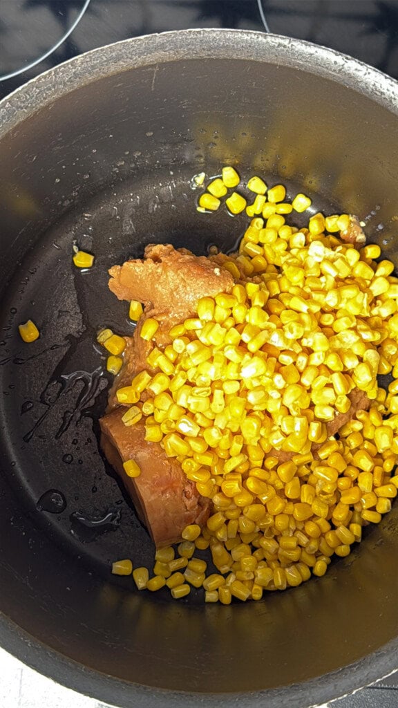 Refried beans and canned corn in a saucepan.