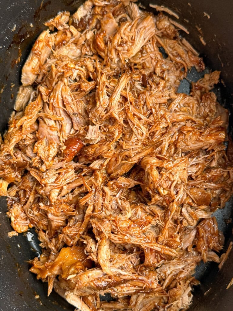 Shredded barbecue pork in a dark pot, coated with a rich brown sauce and pulled into tender, juicy strands.