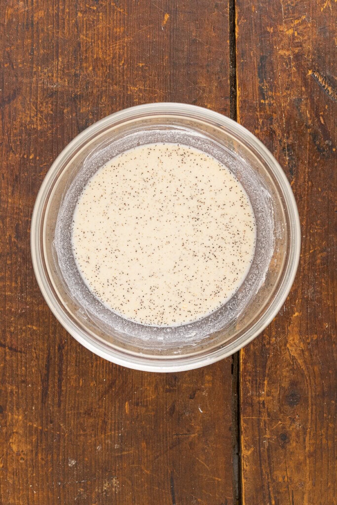 A glass bowl filled with seasonings and milk for condensed soup