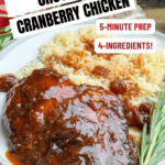 A plate with 4-Ingredient Crock Pot Cranberry Chicken With Catalina Dressing in sauce, served with white rice and garnished with rosemary. Text: Crock Pot Cranberry Chicken, 5-minute prep, 4-ingredients! Get the recipe! backtomysouthernroots.com.