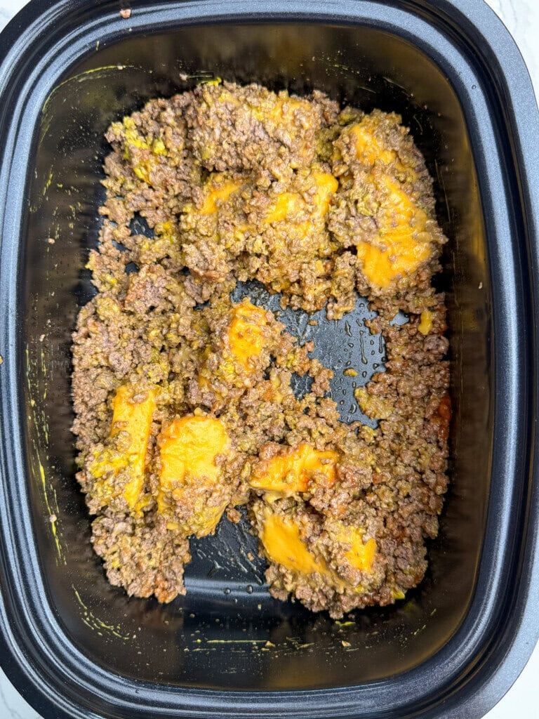 Ground beef mixed with melted cheese in a black rectangular baking dish.