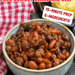 A bowl of Crock Pot Cowboy Beans With Beef And BBQ Sauce sits on a table with a red checkered cloth, accompanied by cornbread, with text promoting this easy crock pot recipe featuring just 6 ingredients and a 15-minute prep time.